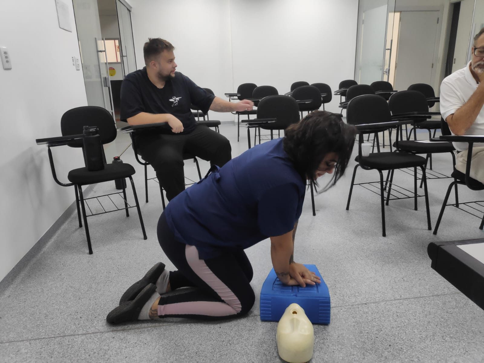 Participante praticando compressões torácicas em manequim